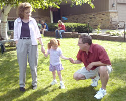 Image of Jeanne and Neal Binsfeld guide their daughter, Hannah, 5, as she walks in the family's front yard July 12. Hannah, adopted at 9 months, is blind and has epilepsy.  (The Catholic Spirit Photo/Dianne Towalski)