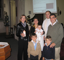 Image of GODPARENTS PARTICIPATE IN BAPTISM VIA INTERNET – The godparents of baby Alban Roger Galiot Marie, held by his mother, Astrid Miorcec de Kerdanet, at his baptism ceremony in Devonport, New Zealand, in June, were able to participate in the child's baptism via Internet video conference from London. Pippa Turley, left, baptism proxy, and the child's father, Gael Miorcec de Kerdanet, are also shown with his sons, Aymeric and Gulihem, and Father Chris Brady, who baptized the baby and came up with the idea of the Internet hookup. (CNS/New Zealand Catholic) 