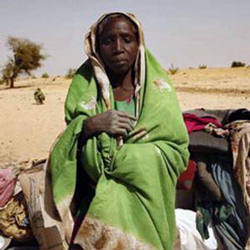 Image of A newly arrived refugee from the Darfur region of Sudan rests next to her belongings in Seneit, Birak area, eastern Chad.