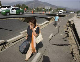 Image of A woman walks by a destroyed road in Santiago, Chile, after a magnitude 8.8 earthquake hit the country early Saturday.