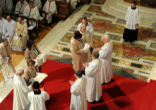 Image of The wives of the first three priests of the Anglican ordinariate in the Catholic Church bring forth their priestly vestments during the Rite of ordination in Westminster Cathedral.
