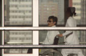 Image of Chen being wheeled by a window in a hospital where he is being held against his will 