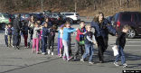 Image of Children with their eyes closed being escorted from their classrooms. 