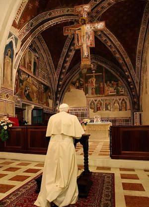 Image of Pope Benedict XVI prays underneath the Saint Damian Crucifix.