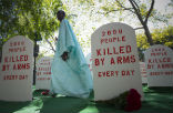 Image of An activist walks amongst a display designed to raise awareness about arms trafficking. 