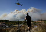 Image of An area resident looks on as helicopters are used to fight the flames. 