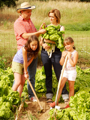 Image of Children woking along parents to grow vegetables for the family.