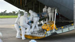 Image of Medics load an infected Ebola patient onto a plane for medical transport.