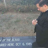 Image of Fr. Pavone prays at the graveside of the children
