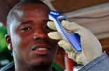 Image of A Liberian man is having his temperature taken by a no-contact thermometer.