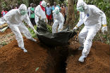 Image of Aid workers in Liberia bury the body of an Ebola victim.