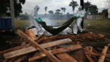 Image of Aid workers in protective suits dispose of the bodies of Ebola victims.