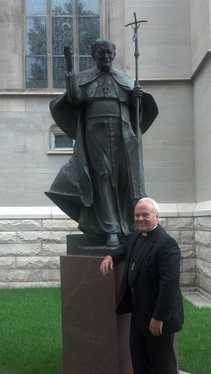 Deacon Keith Fournier standing under the beautiful bronze statue of John Paul II in Denver, Colorado.