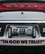 Image of 'In God We Trust' bumper sticker on a patrol car. 