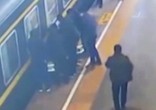 Image of Passengers rally together to pull the child from the tracks (CGTN/YouTube).