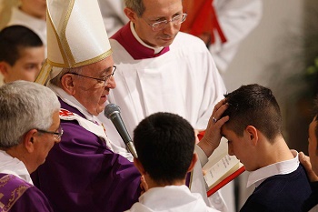 Pope Francis conferring the Sacrament of Confirmation on a young man.