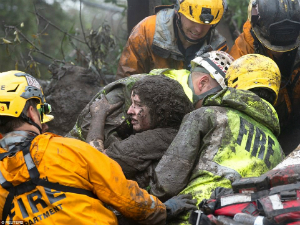 A woman is rescued by firefighters. At least 15 are dead, and search and rescue efforts are ongoing.