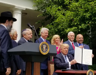 Priests for Life's Alveda King, second from left, watches as President Trump signs an executive order on religious liberty in May 2017.