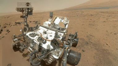 A selfie from the Curiosity rover. Curiosity looks small but is actually the size of a compact car. Fun Fact: Mars is the only planet inhabited entirely by robots.