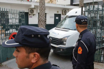 Moroccan security forces stand guard as a van leaves the court