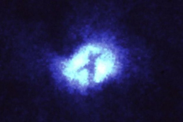 Image of At the heart of Messier 51 (The Whirlpool Galaxy) the Hubble Space Telescope captured the image of a cross. The feature is caused by lanes of dust blocking the light from the galaxy's core.