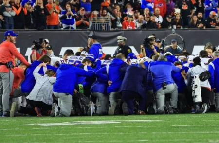 Image of The Buffalo Bills team gathers in prayer following the near-fatal collapse of Damar Hamlin on the field. 