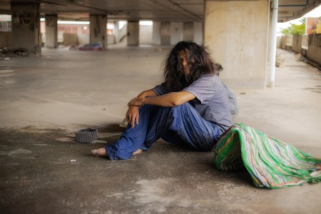 Image of Upset homeless teenager wearing hoodie, feeling cold, indifference and poverty.