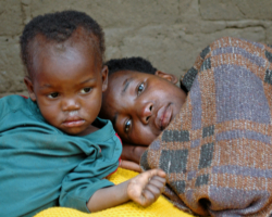 Image of CHILD SITS NEXT TO ILL MOTHER - One of her children sits next to an ailing Lydia Kathebwe, 31, infected with HIV, in the Zamba district of Malawi in this photo taken in late May. Father John Garvey explores the issue of suffering, asking whether God can be all powerful and all good and the world be a place of much misery. (CNS/The Catholic Register)
