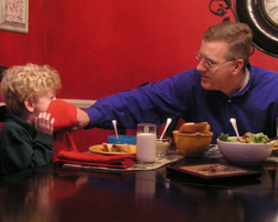 Image of LENTEN FOOD FOR THOUGHT – Howard Egger wipes the face of his son, Charlie, during dinner – a time when the Egger family regroups and prays together. The start of Lent provides food for thought, not only about food but about the importance of the Lenten season in the faith lives of people. (The Criterion)