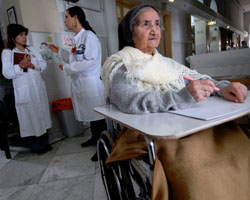 Image of PATIENT WRITES OUT PRAYERS AT JERUSALEM HOSPICE FACILITY – Sister Constancia Francis, 82, writes out prayers as therapist Tammy Einstein, center, consults with another staff member at Saint-Louis Hospital in Jerusalem March 22. The facility, run by the Sisters of St. Joseph of the Apparition, provides hospice and geriatric care to Jerusalem residents of any race, religion or nationality. (CNS photo/Debbie Hill) 
