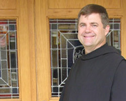Image of BROTHER PATRICK'S LIFE CHANGED ONCE HER HEARD SPIRT IN OTHERS - Brother Patrick Boland, OSB, wears his simple Benedictine habit, which includes a black cassock, leather belt and scapular (similar to priest's alb, minus the sides) with attached capoch (hood). (Photo/Arkansas Catholic)
