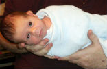 Image of A baby swaddled and held for vaccinations. 