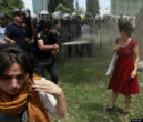 Image of Ceyda Sungur calmly withstanding attack by an officer with pepper spray.