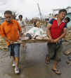 Image of Workers carry the body of a victim to a collection area. 