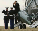 Image of Obama talks on his phone while saluting Marines. 