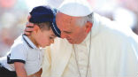 Image of Pope Francis embraces a child in St. Peter's Square. 