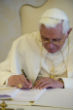 Image of Pope Benedict signs a bound copy of his encyclical. 