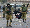 Image of Israeli soldiers carry off wounded Palestinian, who they accuse of going on a stabbing rampage. 