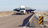 Image of A truck transports a mysterious, covered object to Area 51 under tight security.  
