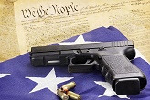Image of Gun on an American flag with the U.S. Constitution in the background