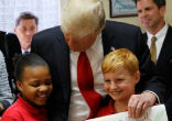 Image of President Trump posed for a picture with two students from St. Andrew Catholic School, telling them 