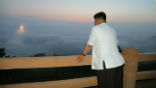 Image of Kim Jong Un views a launch from a distance. 